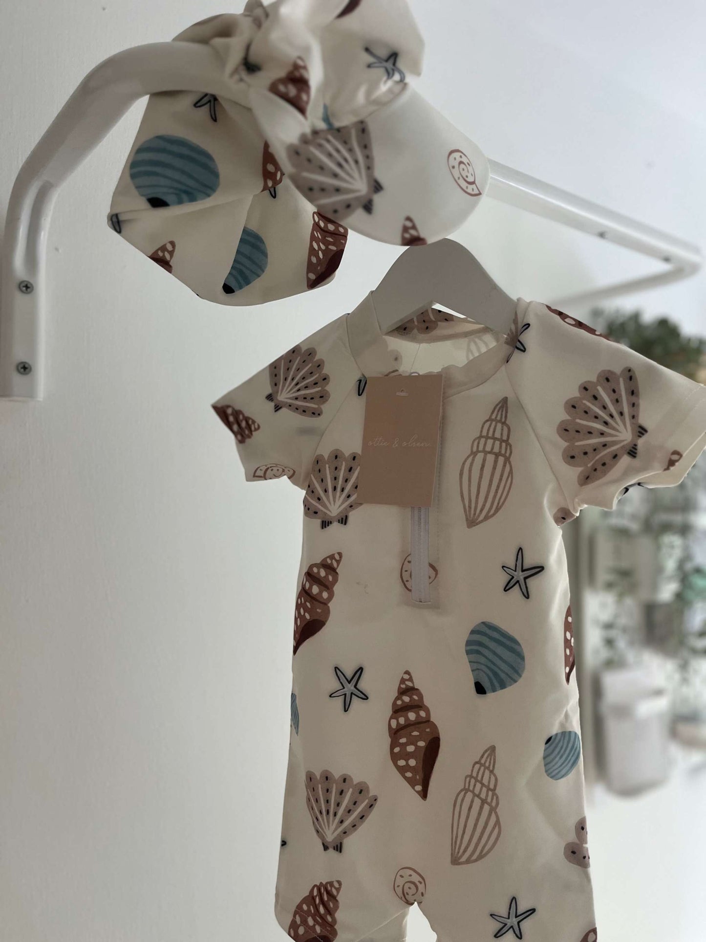 Neutral-toned Oscar Shell Swimsuit and hat set for kids with shell motif and sun protection.