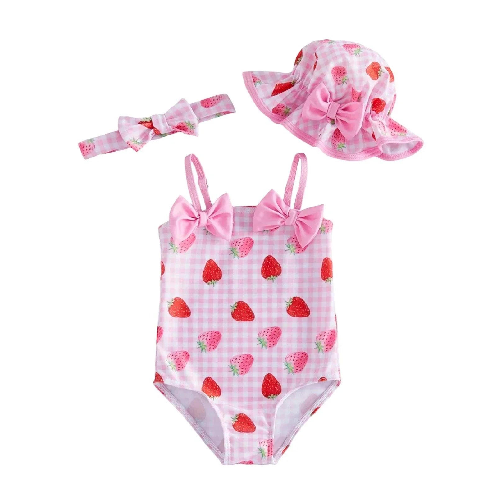 Toddler wearing strawberry swimsuit and bonnet set with matching bow for summer beach fun