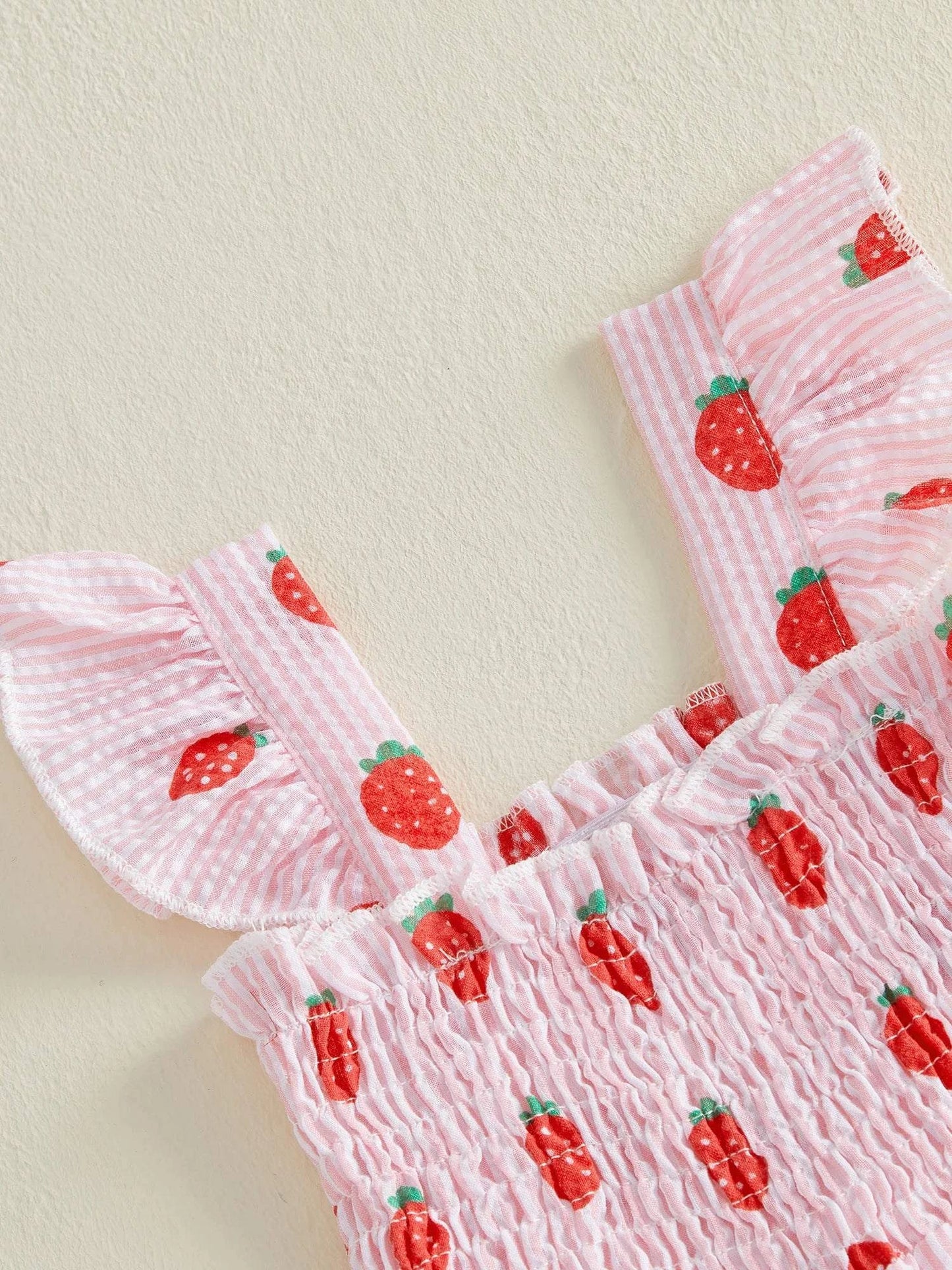 Little girl wearing a lightweight strawberry onesie perfect for summer comfort and breathability